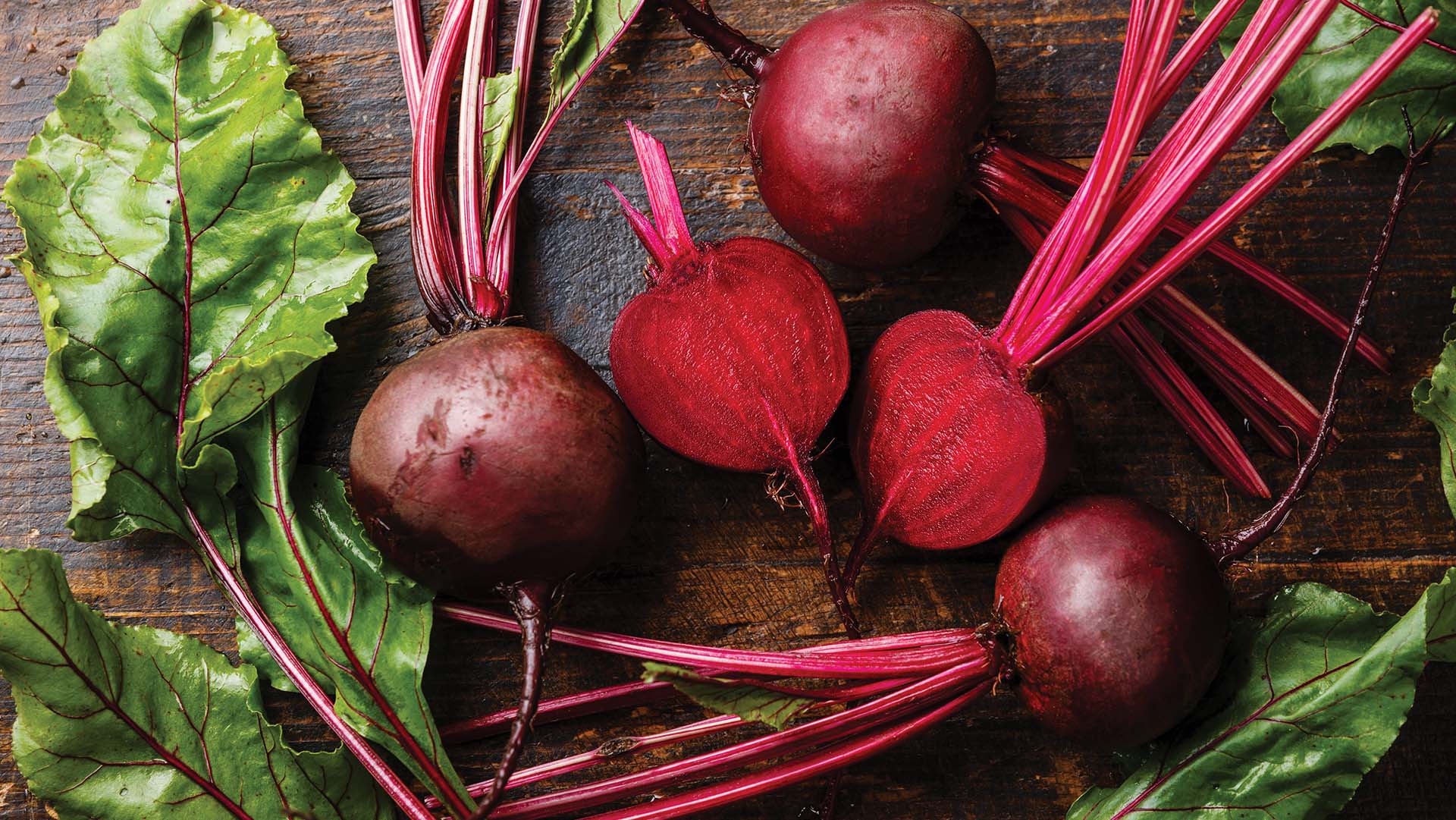 Red Beetroot with herbage green leaves on wooden background