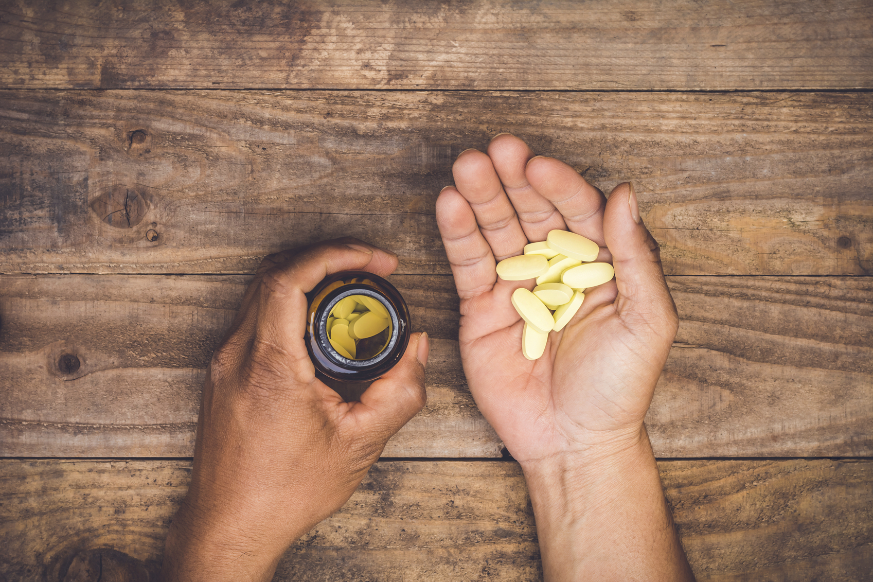 bottle pouring pills on a male's hand