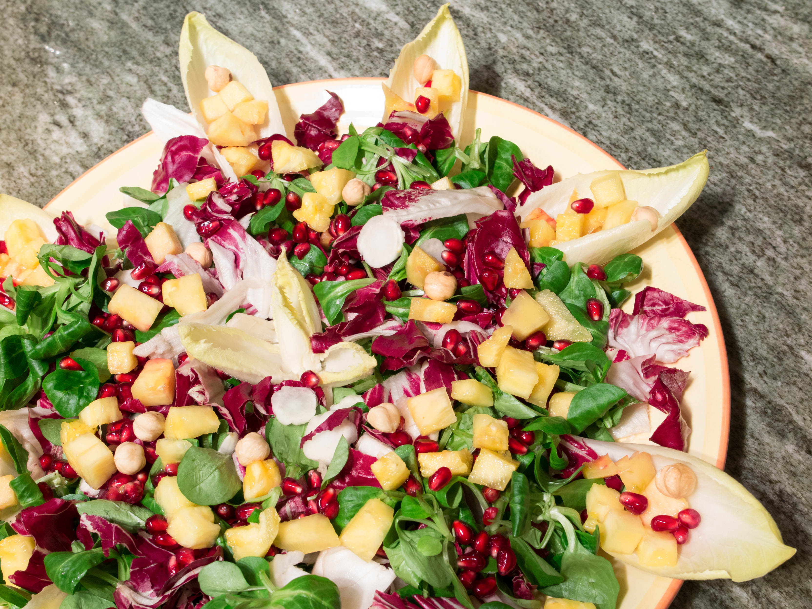 A colorful beautifully displayed dish with mixed salad, vegetables and fruit