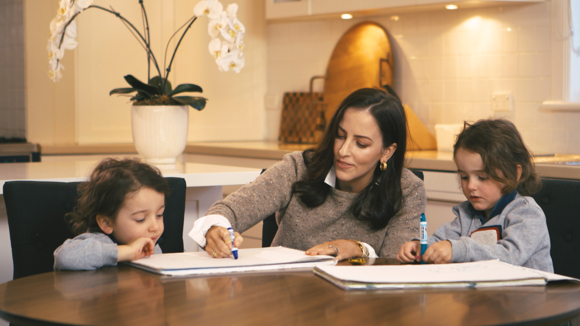 Lisa colouring in at the kitchen table with her two sons.