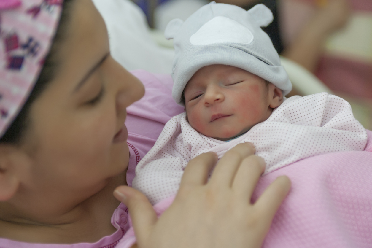 A newborn baby enters the world and mother holding newborn baby girl in the hospital.