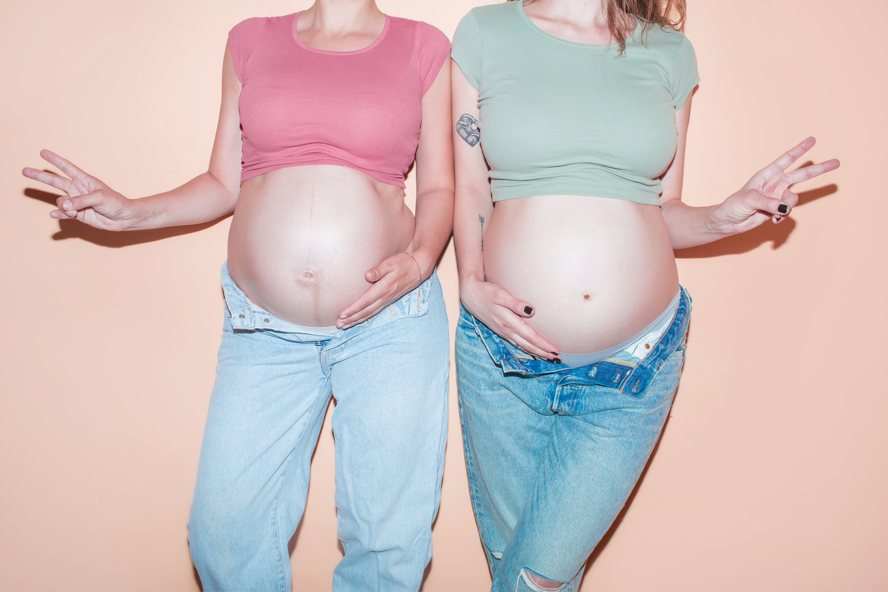 Two pregnant woman showing peace sign