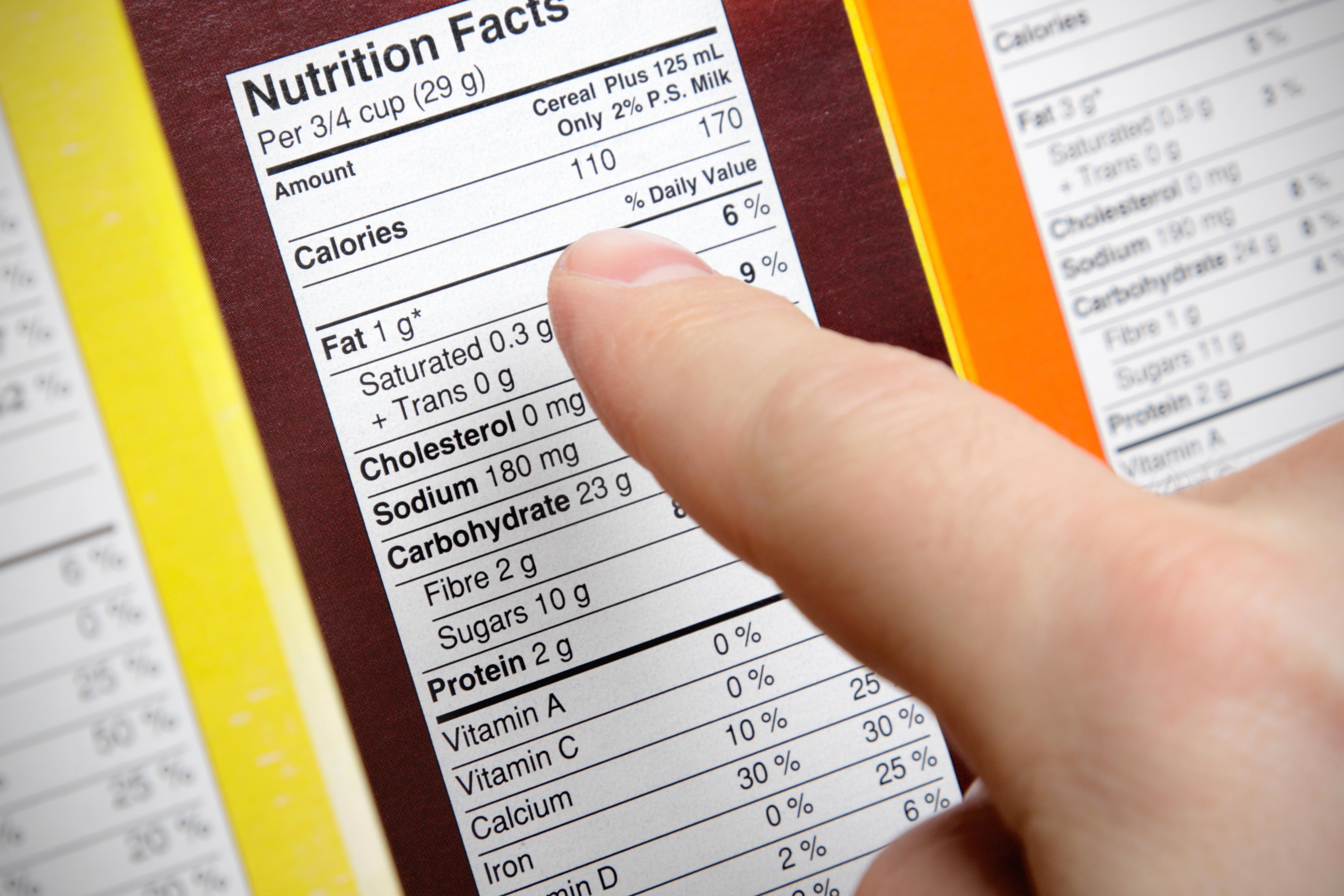 A concerned shopper checks the nutrition labels of various boxes of cereal.