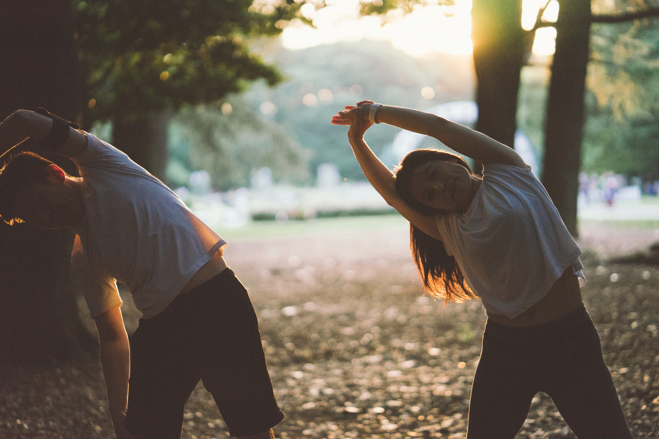 Japanese sport couple stretching outdoors in the early morning, city park on the background.