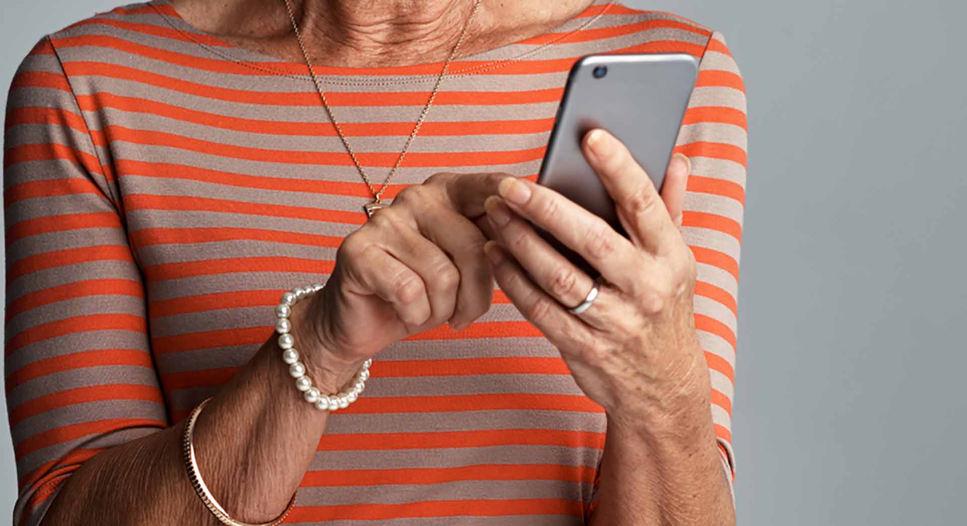 Shot of a senior woman using her cellphone against a grey background