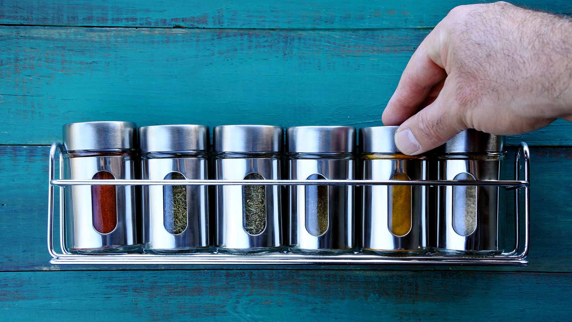 Chef hand returning spice into a spice rack. Food background. copy space