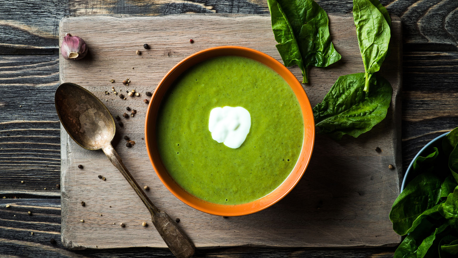 Homemade spinach soup in a bowl on wooden background