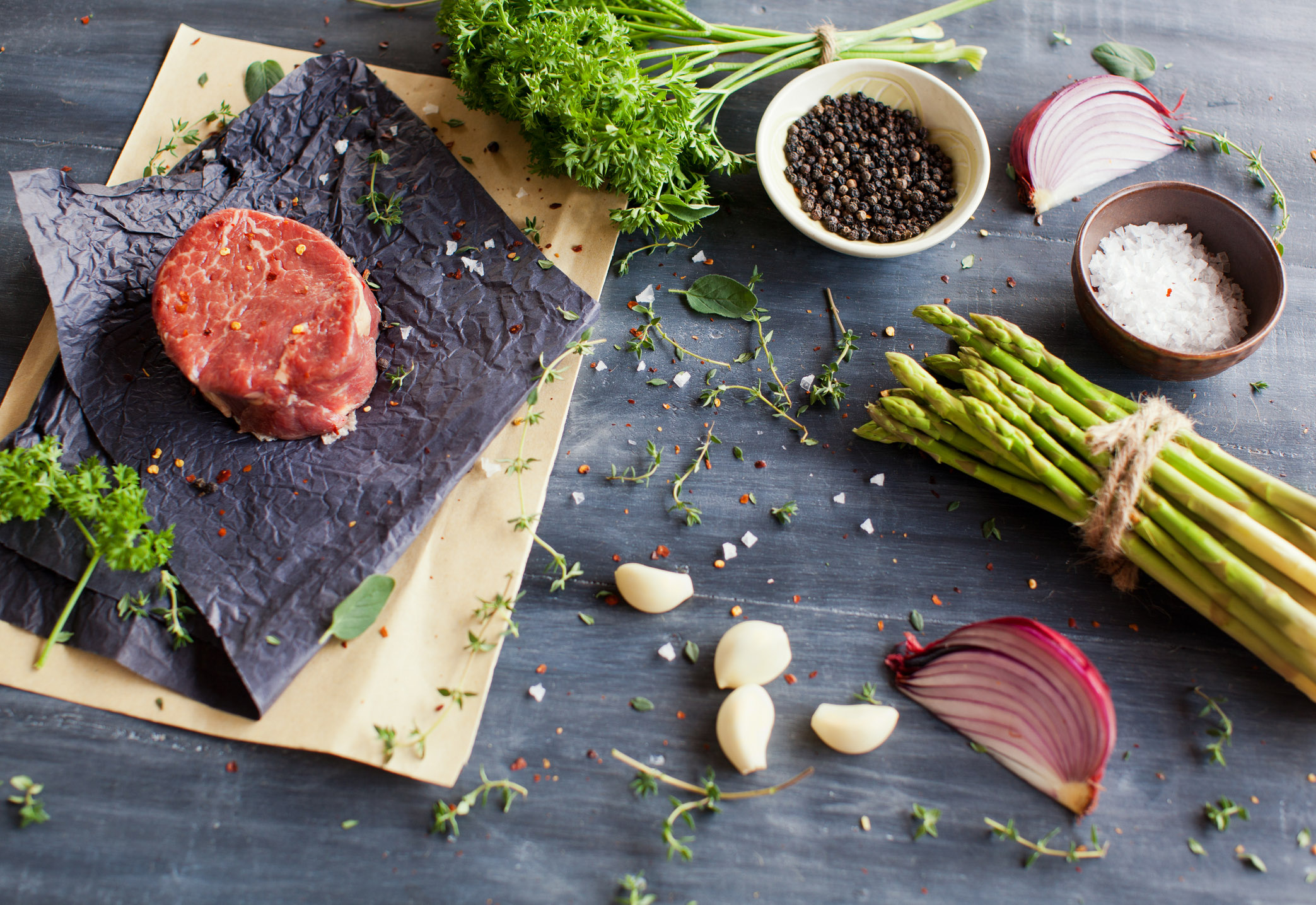 Raw tenderloin steak with seasoning, garlic, and asparagus