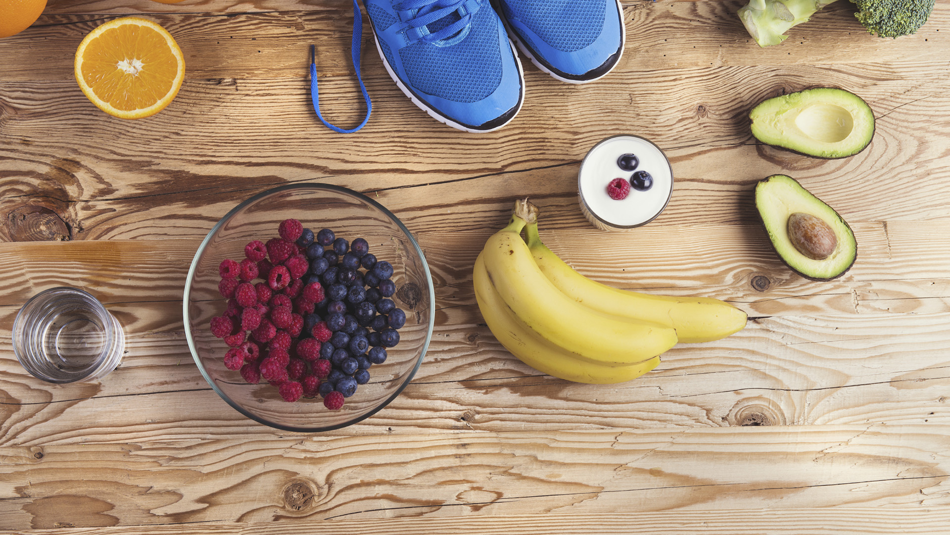 Pair of running shoes and healthy food composition on a wooden table background