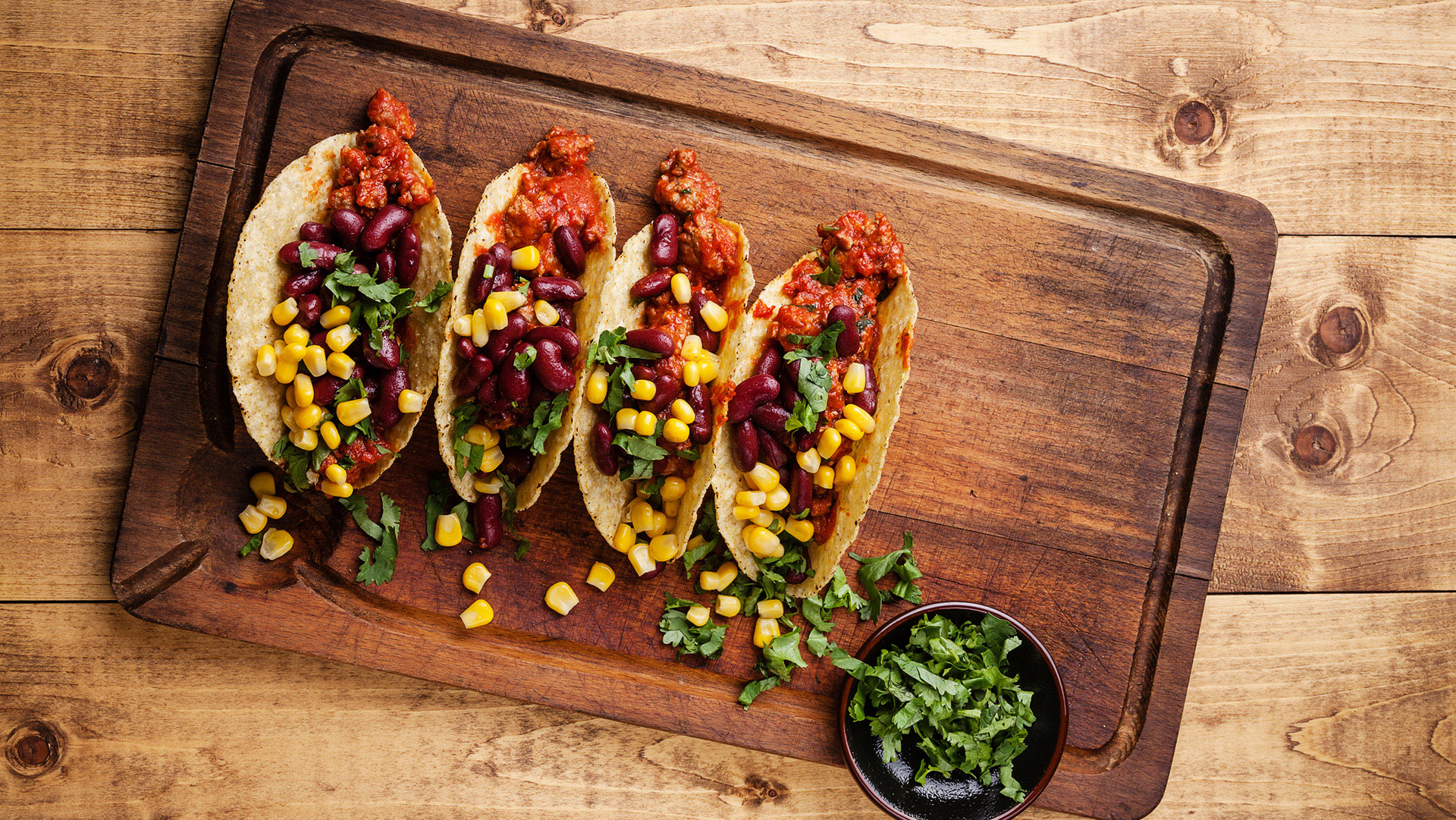 Tacos with ground beef, corn and red beans on wooden table