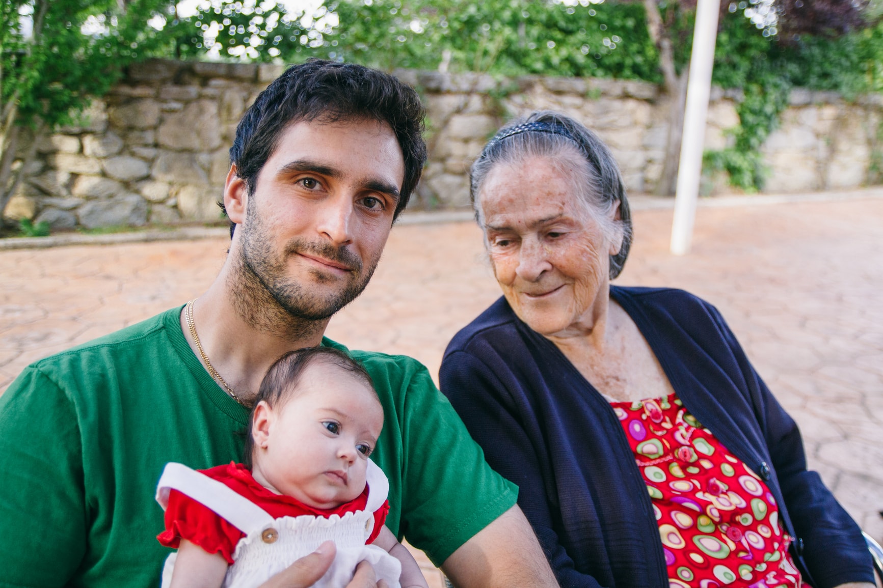 man holding a baby with elderly woman next to him