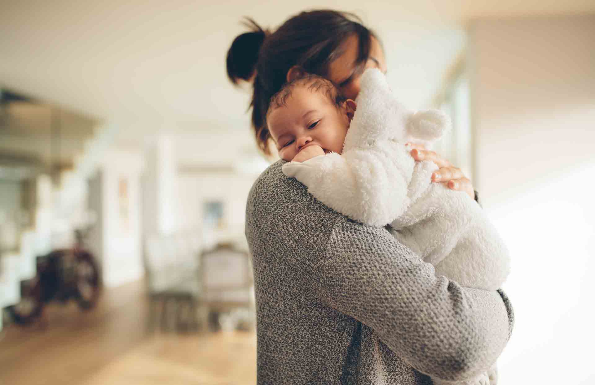 Cute little boy in his mother's arms. Woman at home carrying her newborn son.