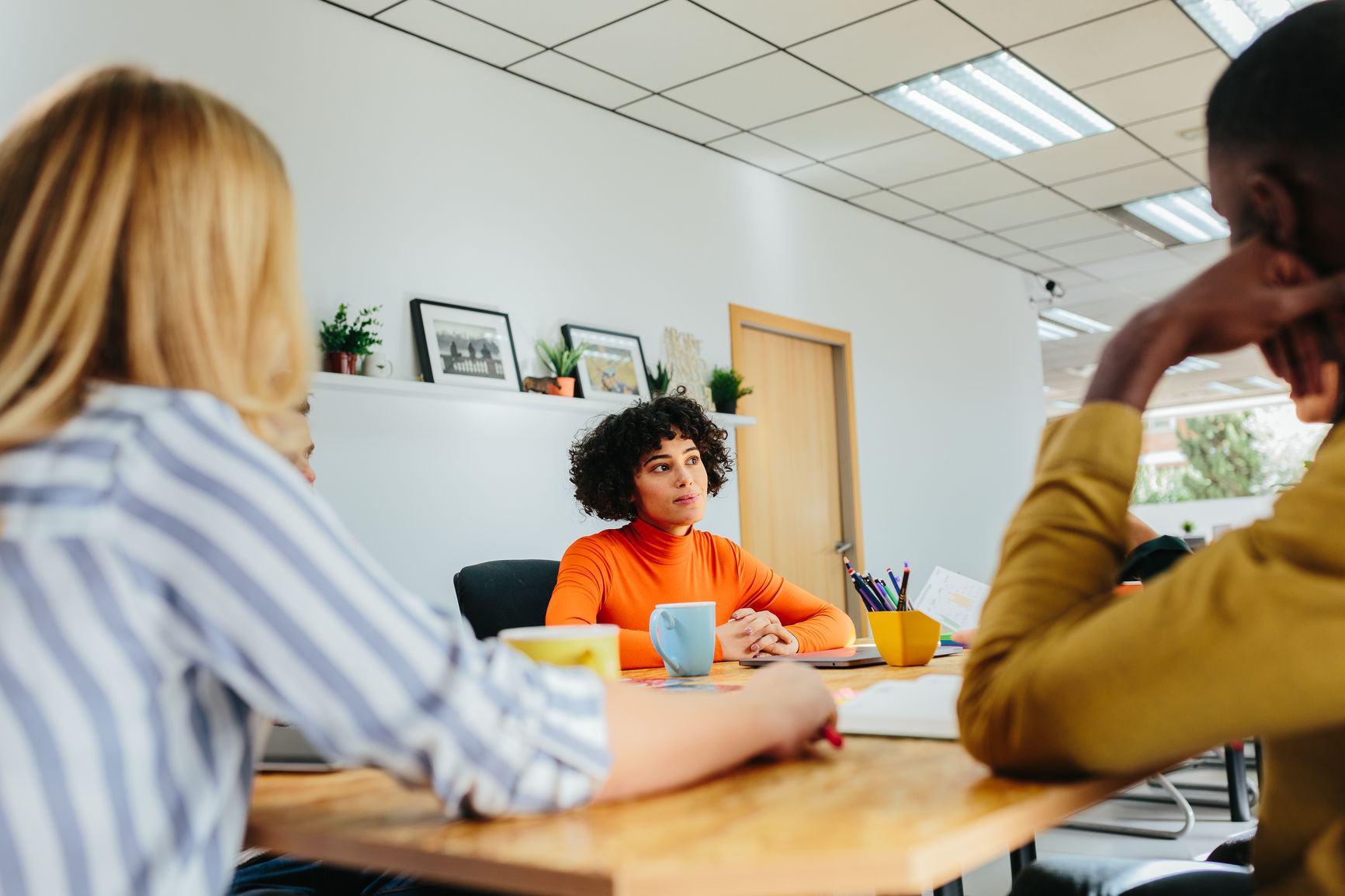 View of multiethnic men and women working together in modern office sitting at desk