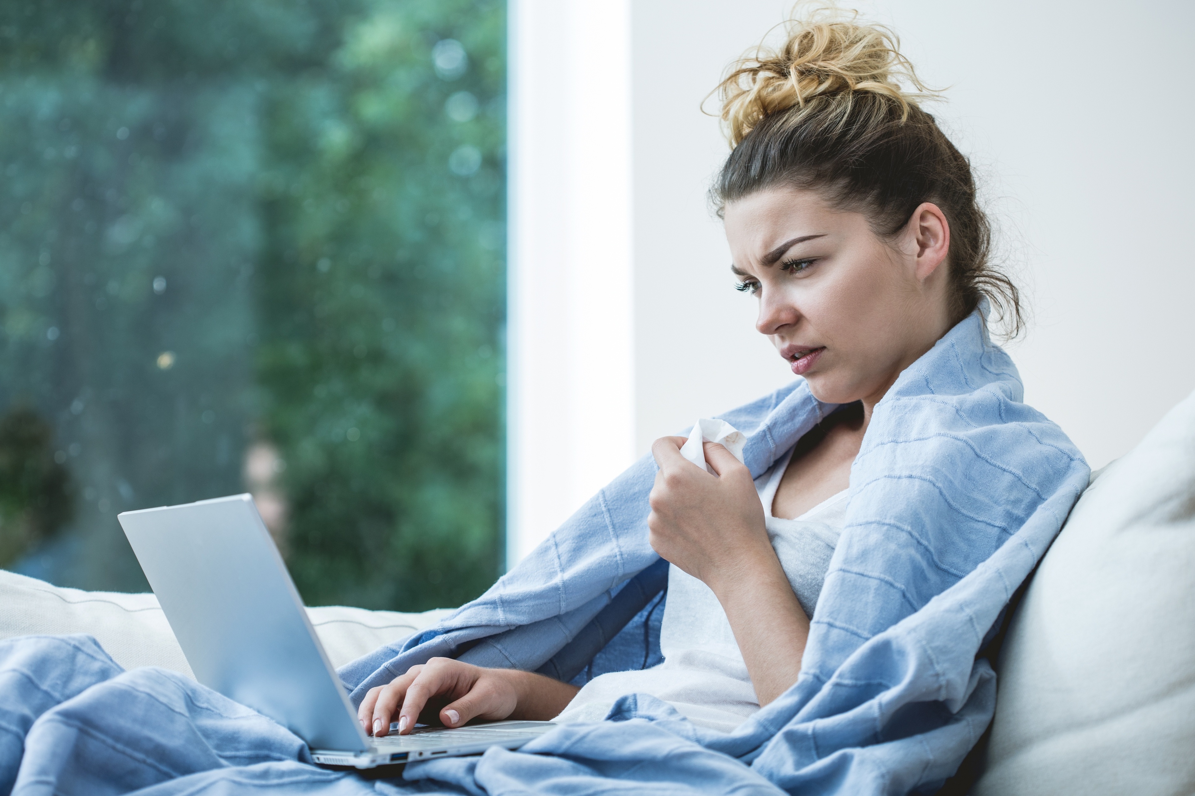 Young ill woman in bed with laptop
