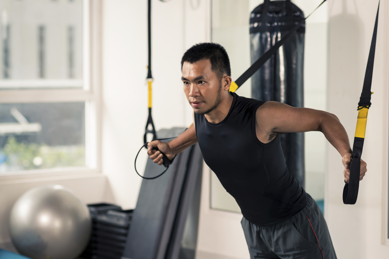 Asian man having fitness TRX training at gym