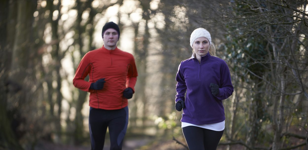 Couple On Winter Run Through Woodland