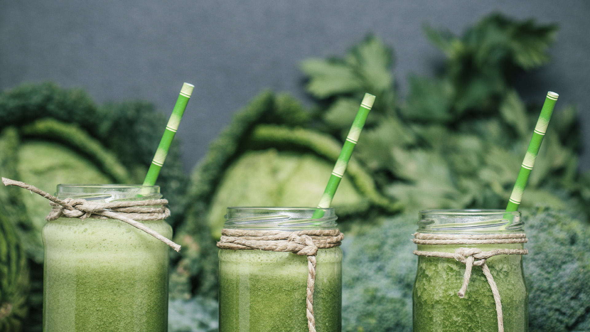 Blended green smoothie with ingredients on wooden table