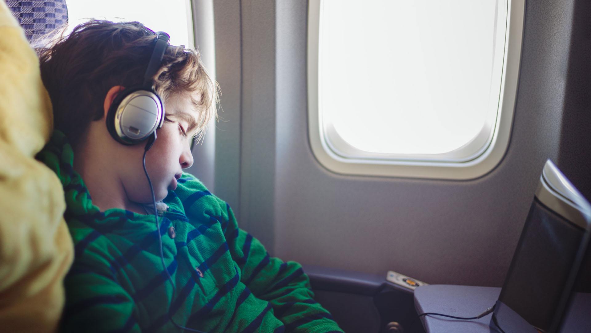 Young boy wearing headphones asleep on an airplane