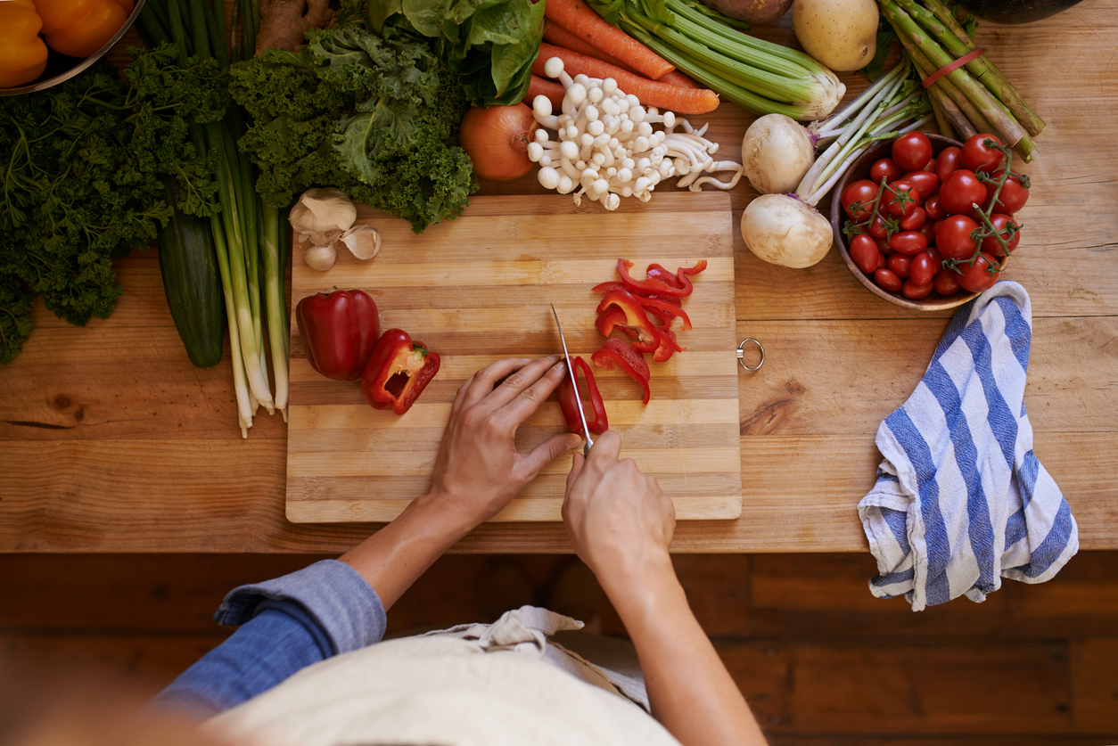 Cropped shot of an unrecognizable woman chopping vegetables on a wooden cutting board