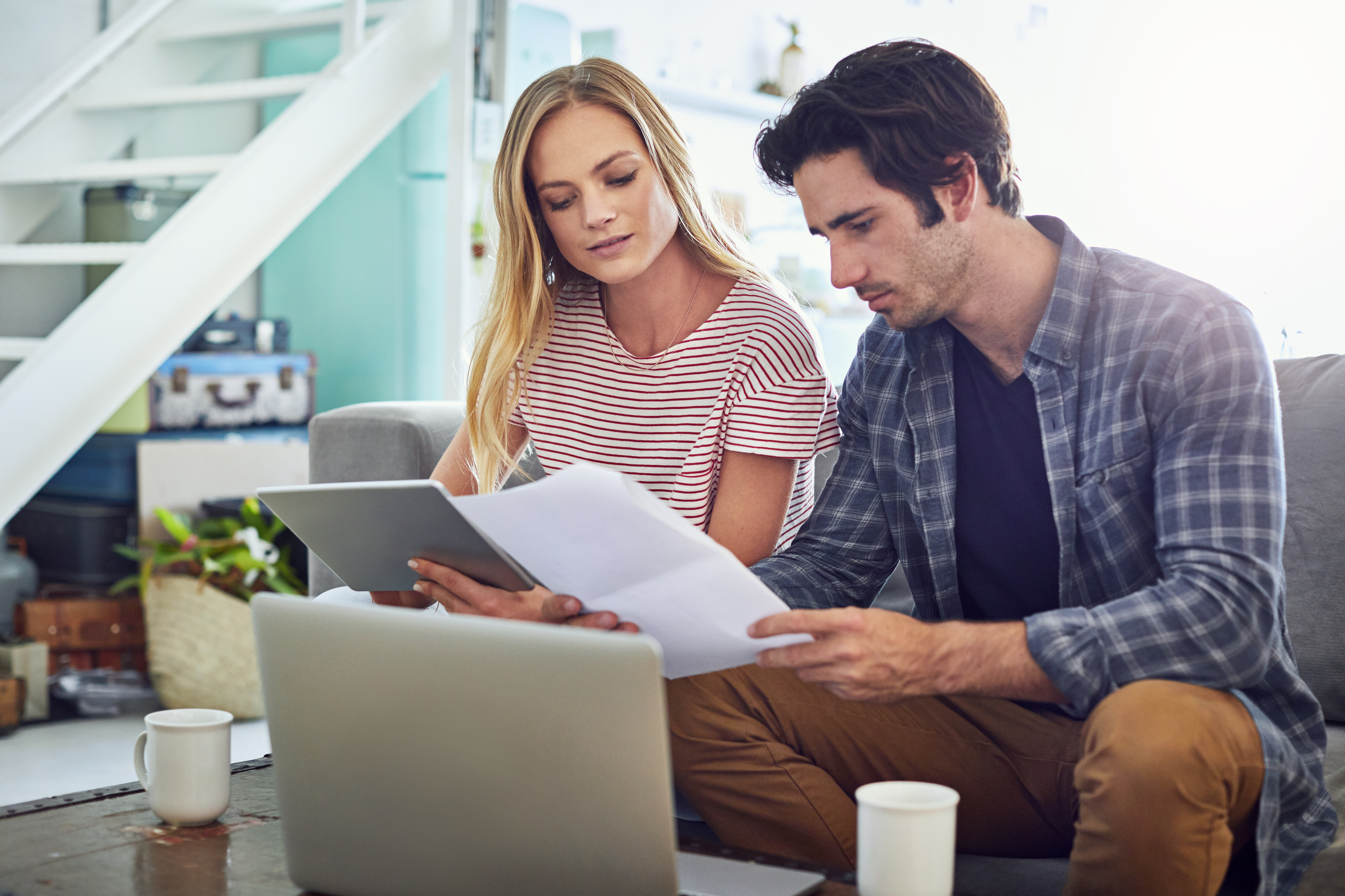 Shot of an affectionate young couple looking over some paperwork at home