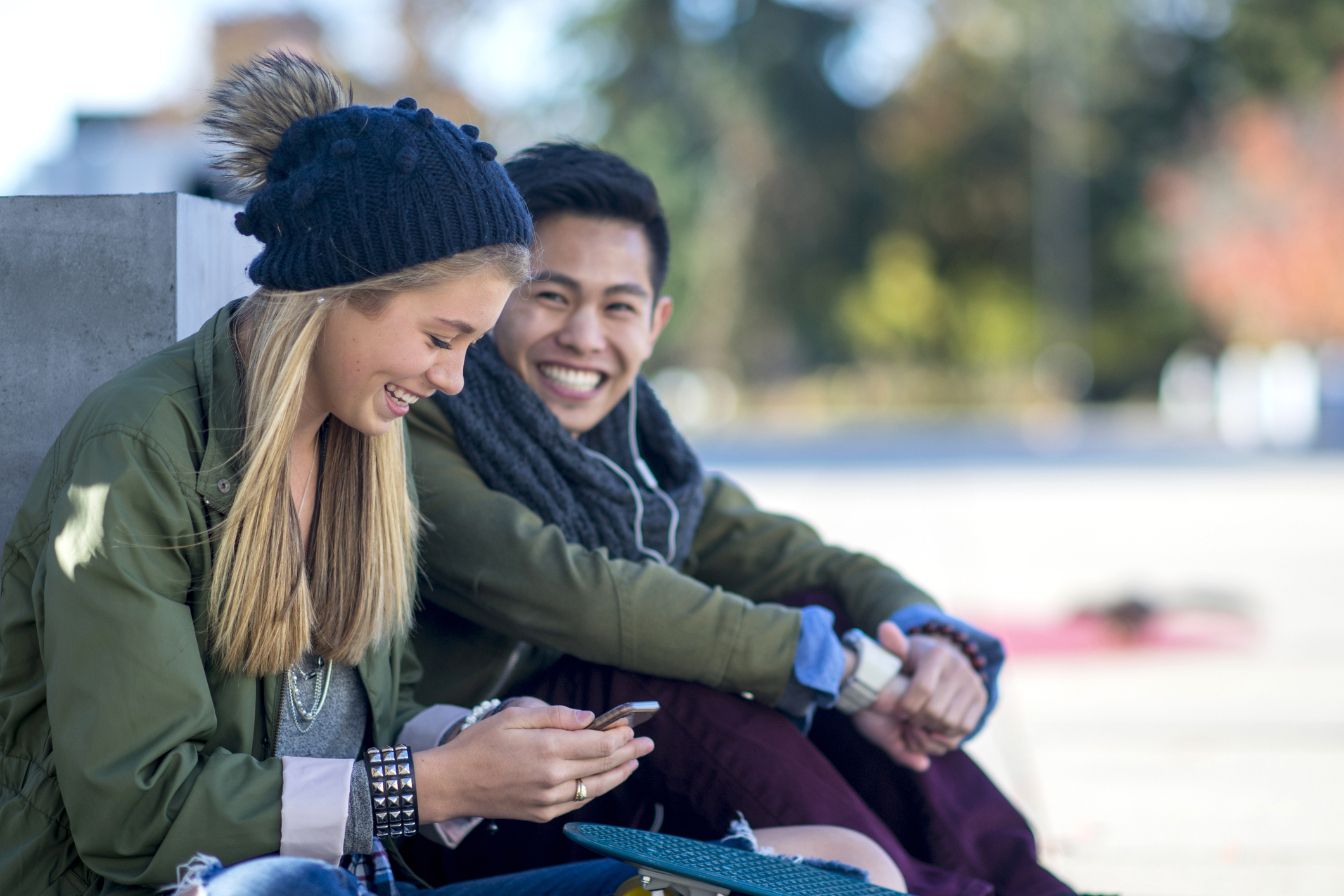 A multi-ethnic couple is sitting outside after class and are spending time together on a sunny day.