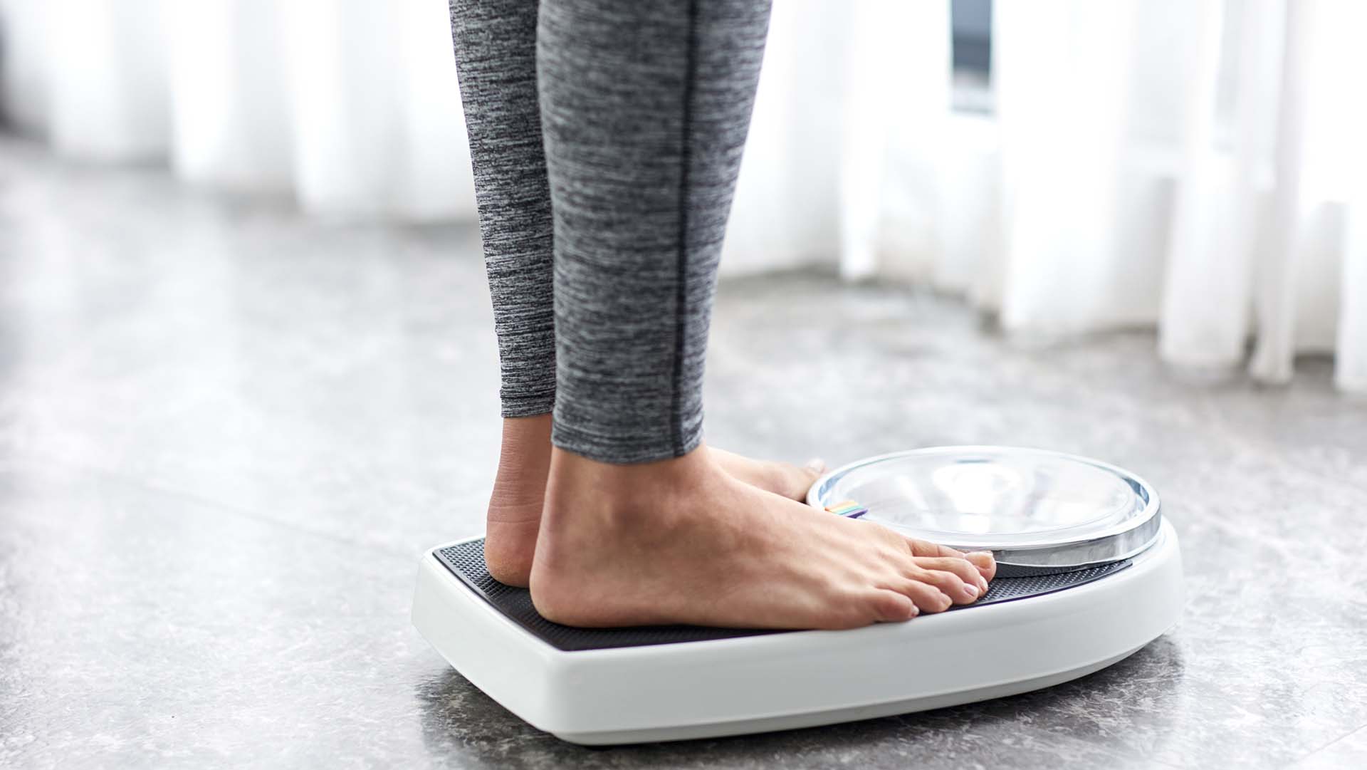 Young healthy girl on home scales