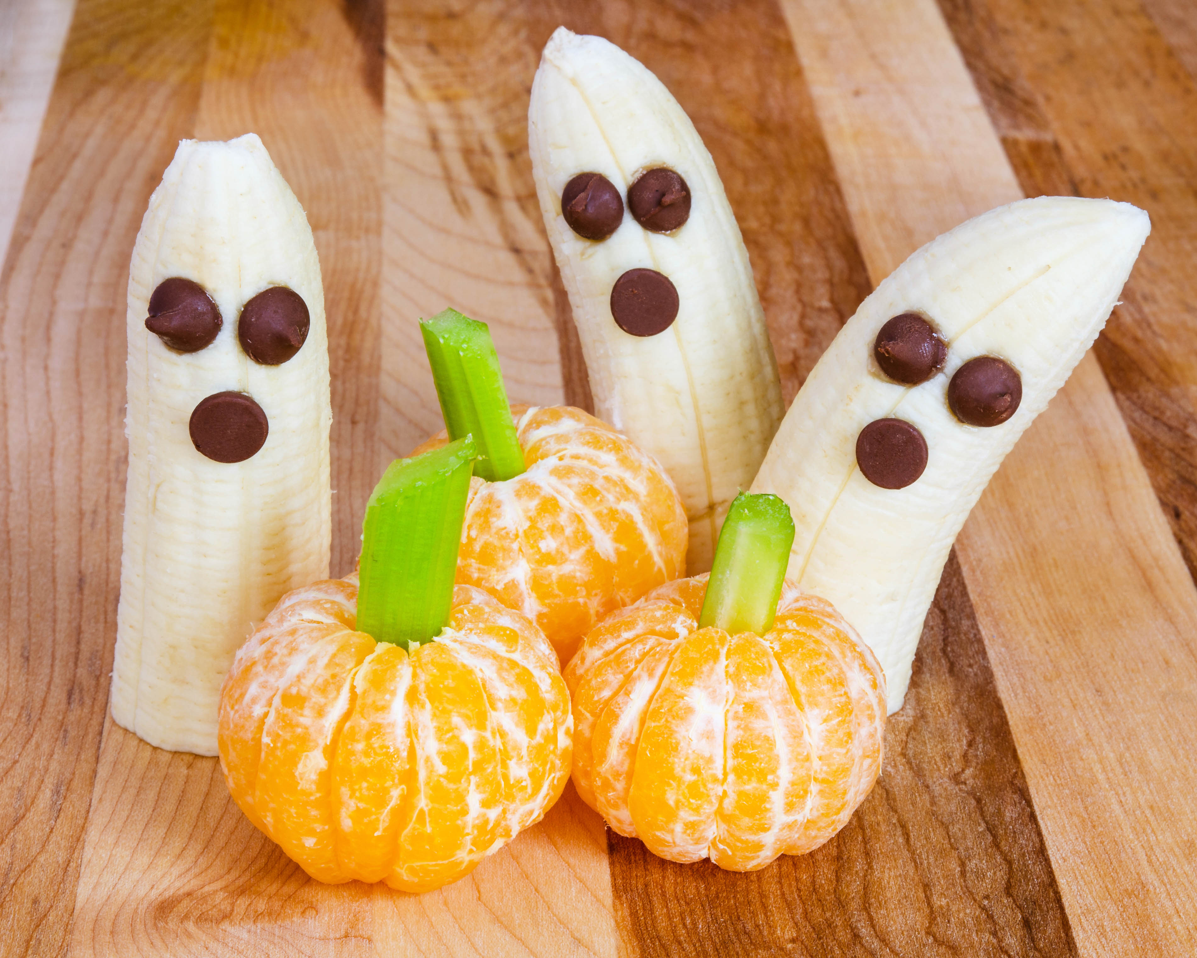 Halloween child friendly treats with bananas and clementines made to look like pumpkins and ghosts