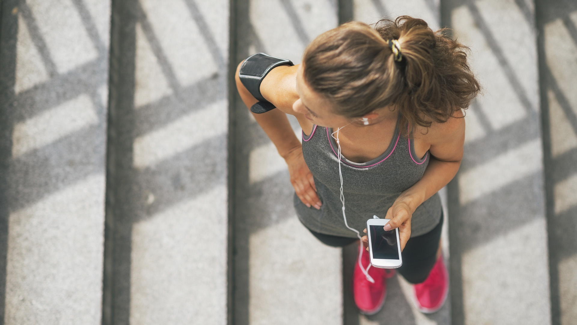 Portrait of fitness young woman with cell phone outdoors in the city