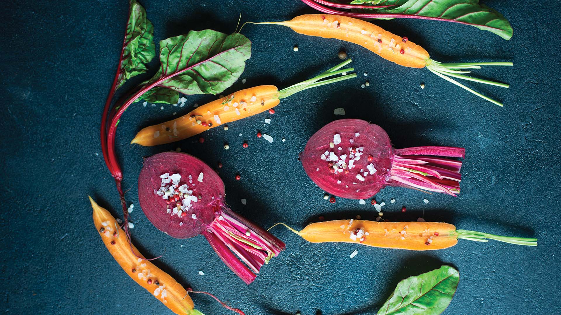 Fresh raw summer vegetables, beetroot and carrot, over dark background
