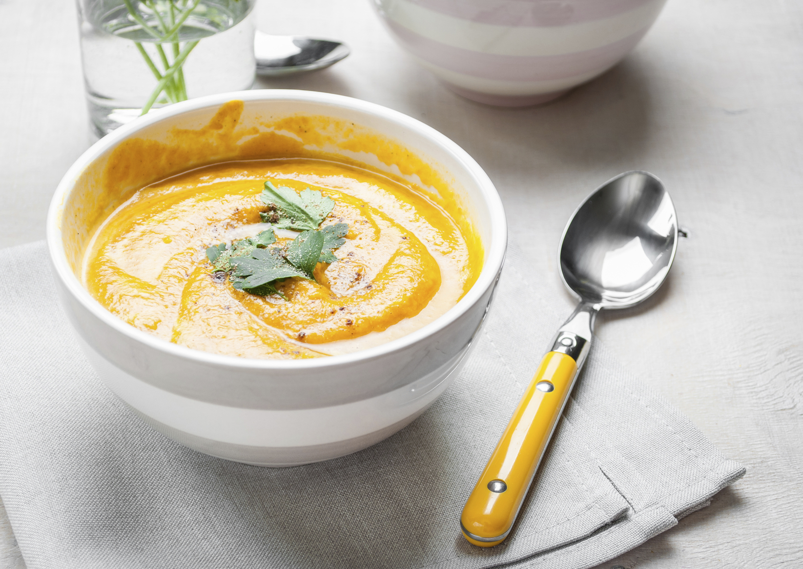 Pumpkin soup with parsley on grey napkin background