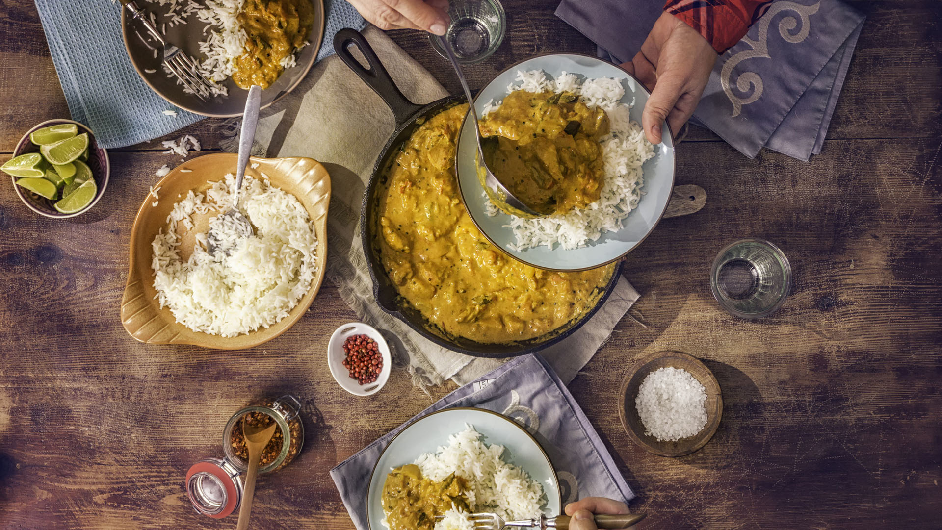 Young family eating delicious homemade chicken curry dish with basmati rice.