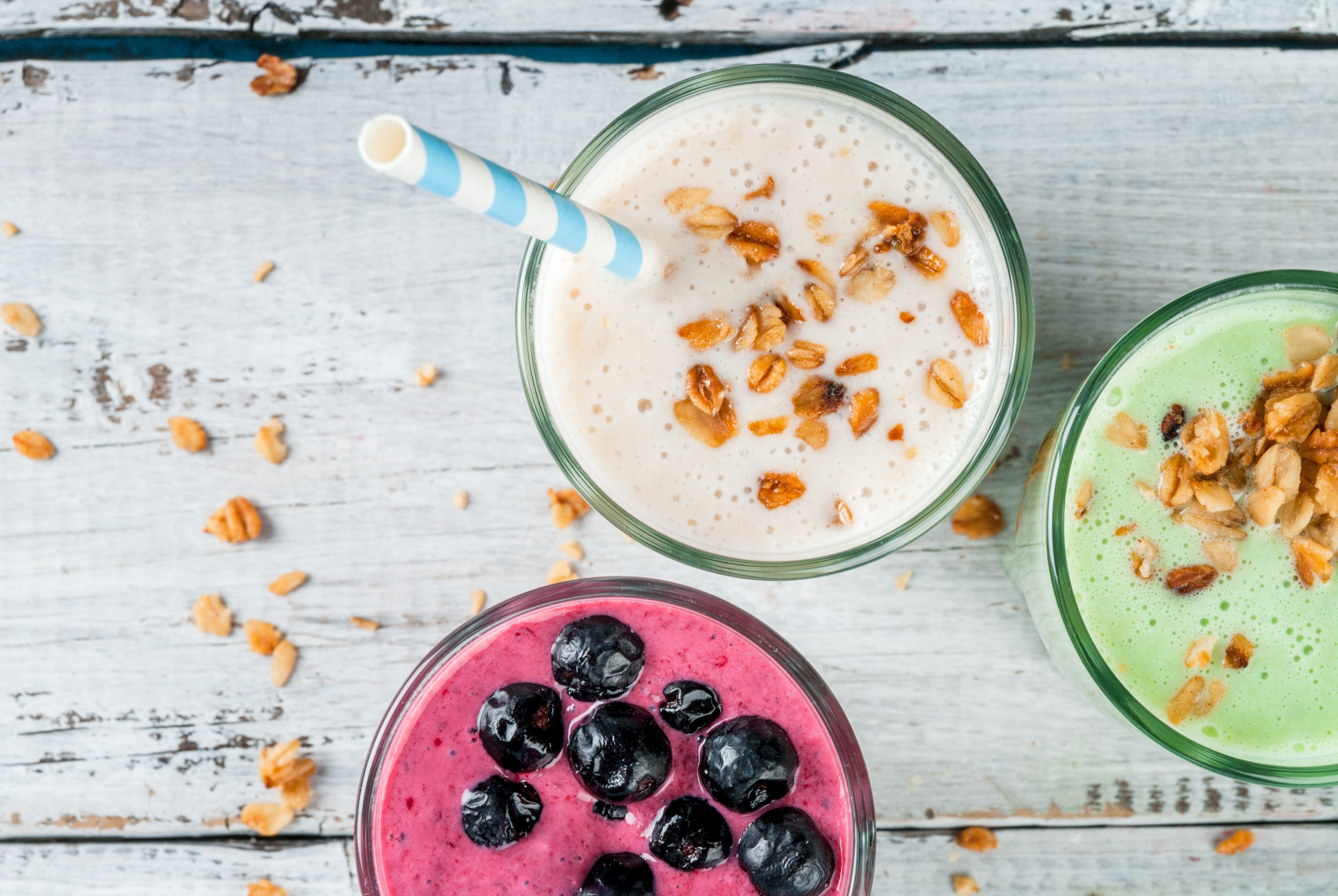 Refreshing milkshakes or smoothies: White (banana), green (apple and kiwi) and berries; with fresh fruits. On a white wooden table, copy space