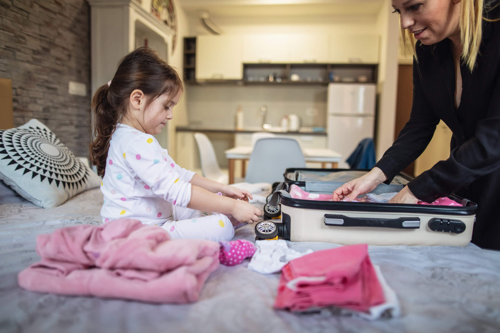 Woman and child packing small suitcase