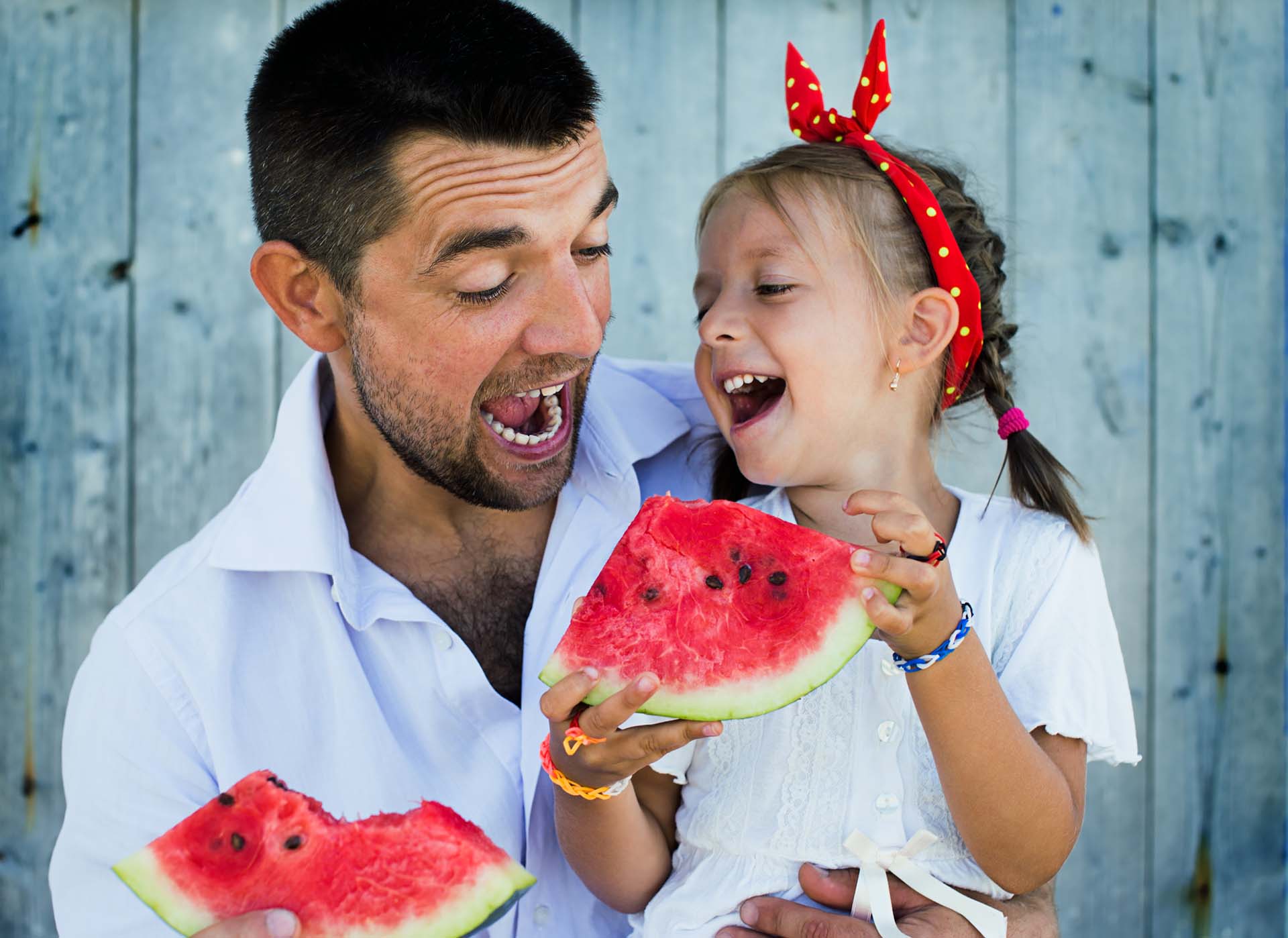 happy father playing with cute little daughter holding  watermelon