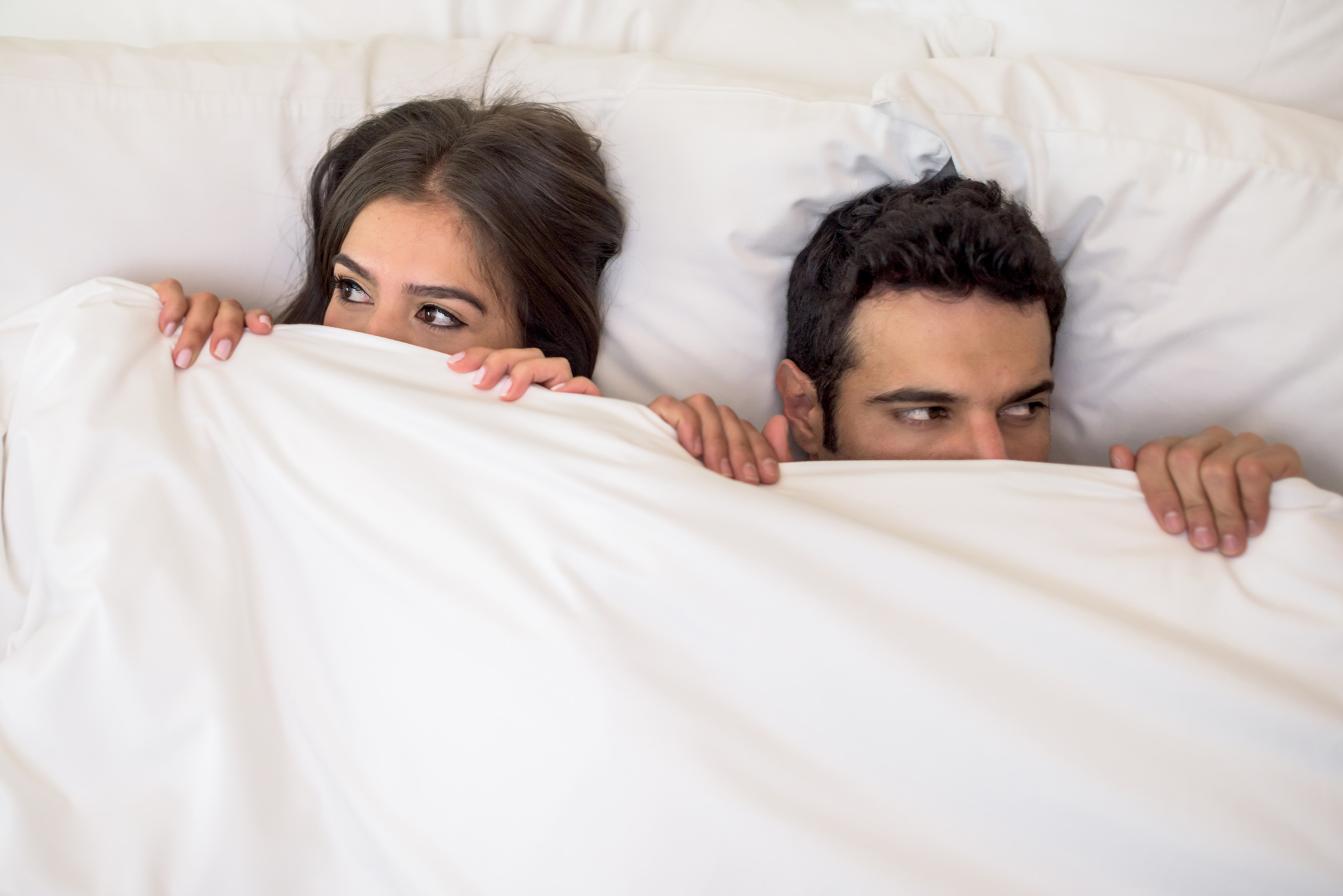 Portrait of a scared couple in bed with man and woman looking very anxious