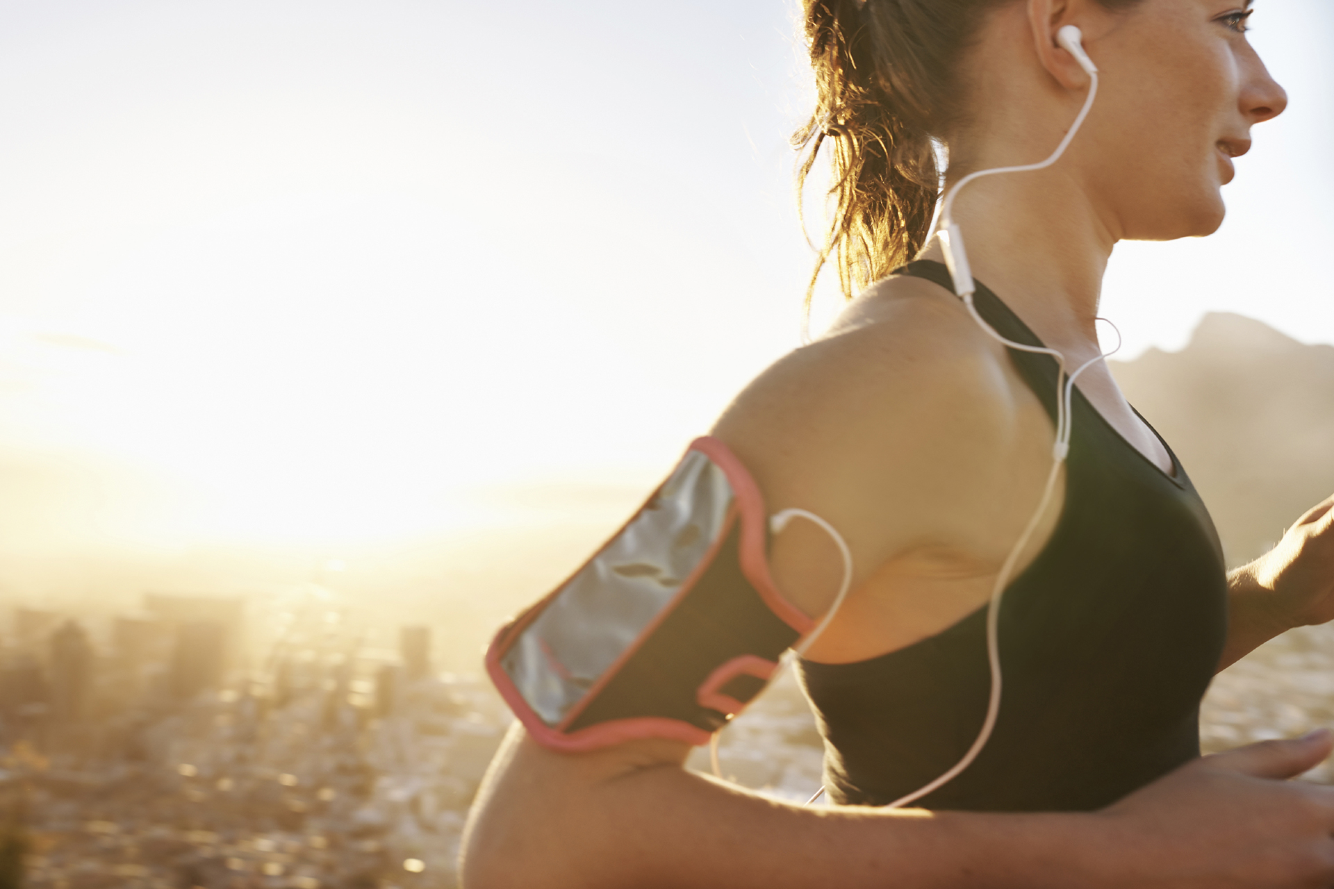 Cropped shot a beautiful young woman training outdoors while listening to music