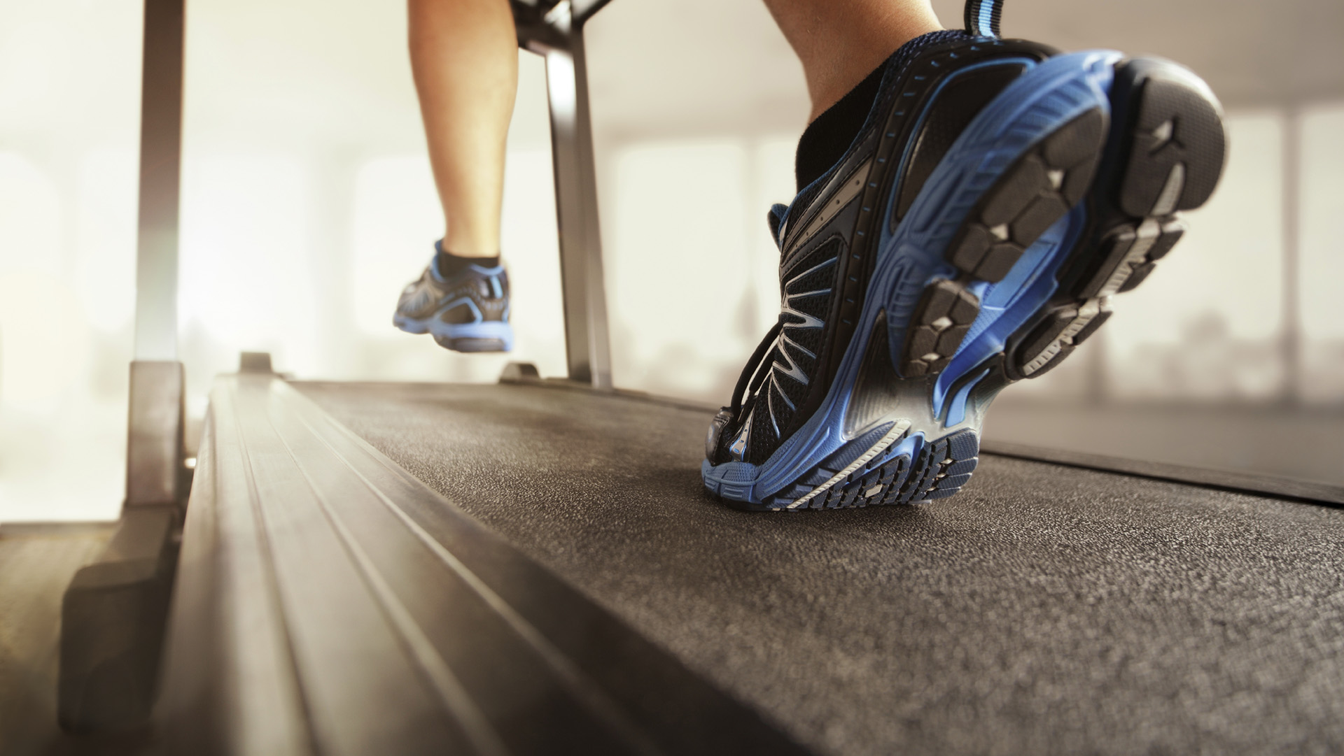 Man running in a gym on a treadmill concept for exercising, fitness and healthy lifestyle