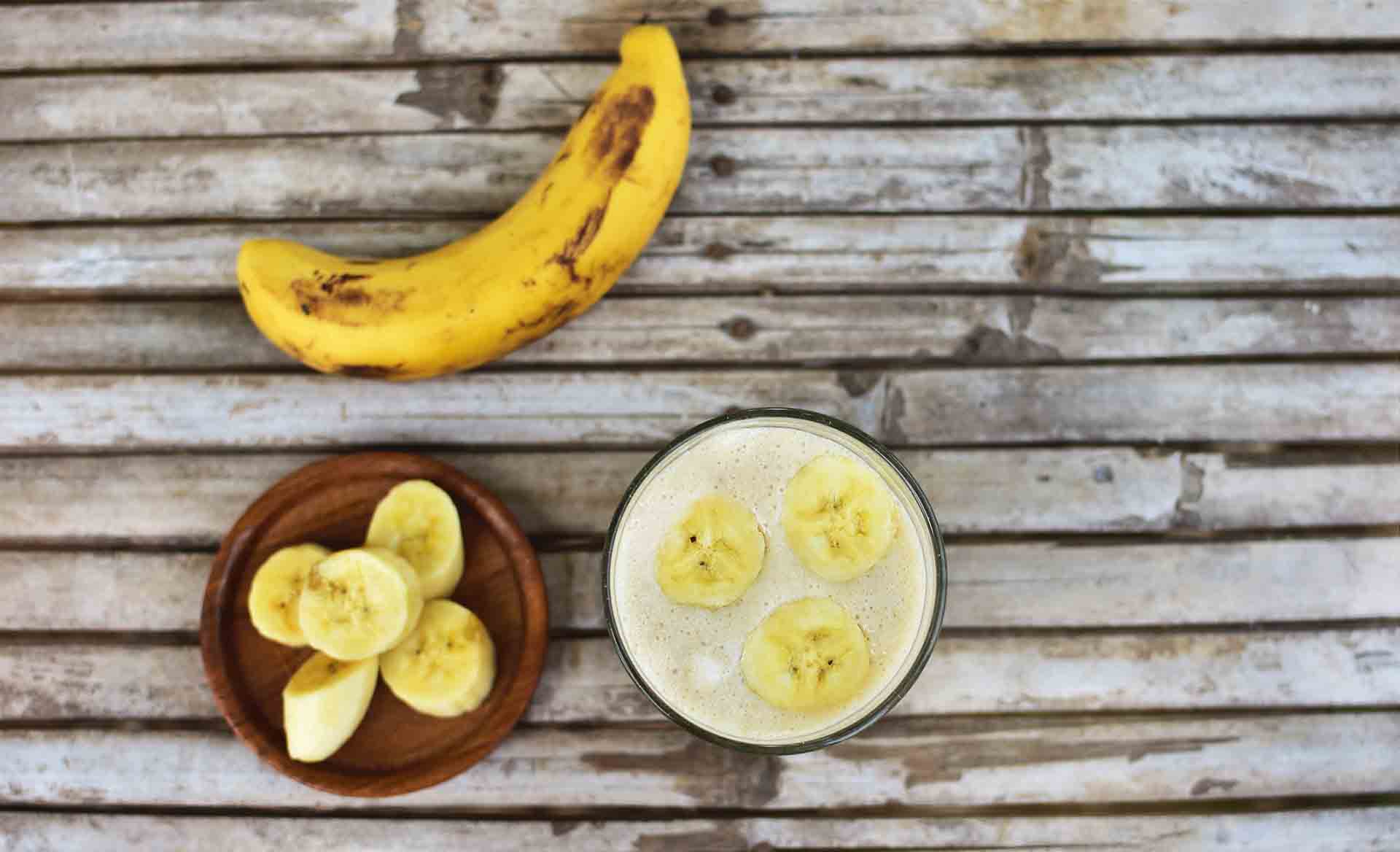 Healthy smoothie with banana on wooden background.