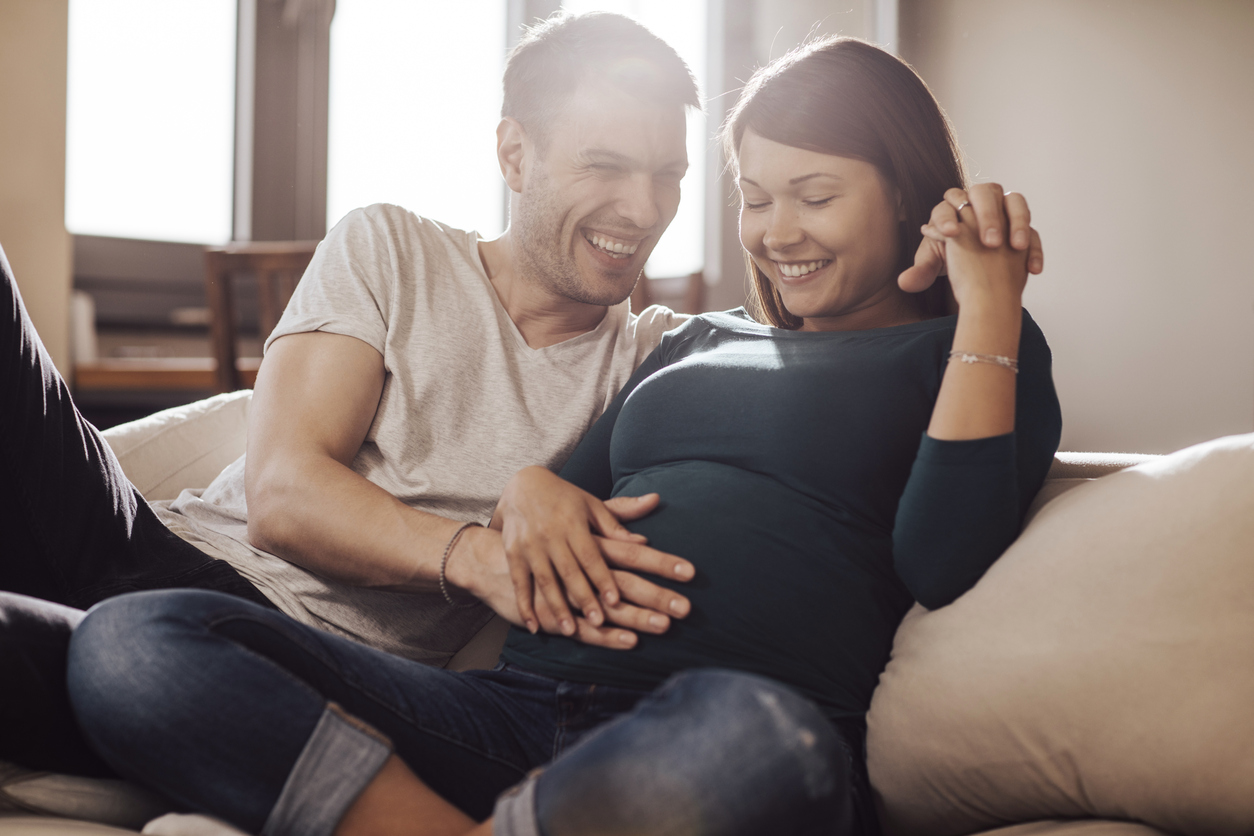 Husband touching wife's stomach, trying to feel baby.