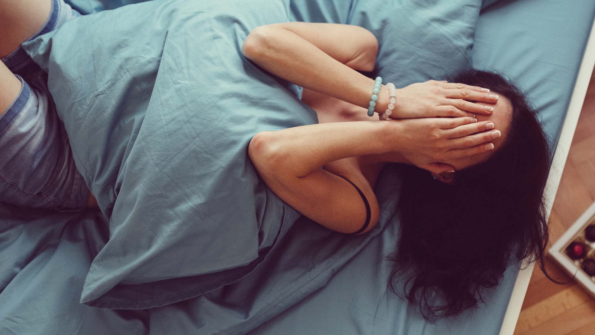 Depressed woman in bed with hands on face