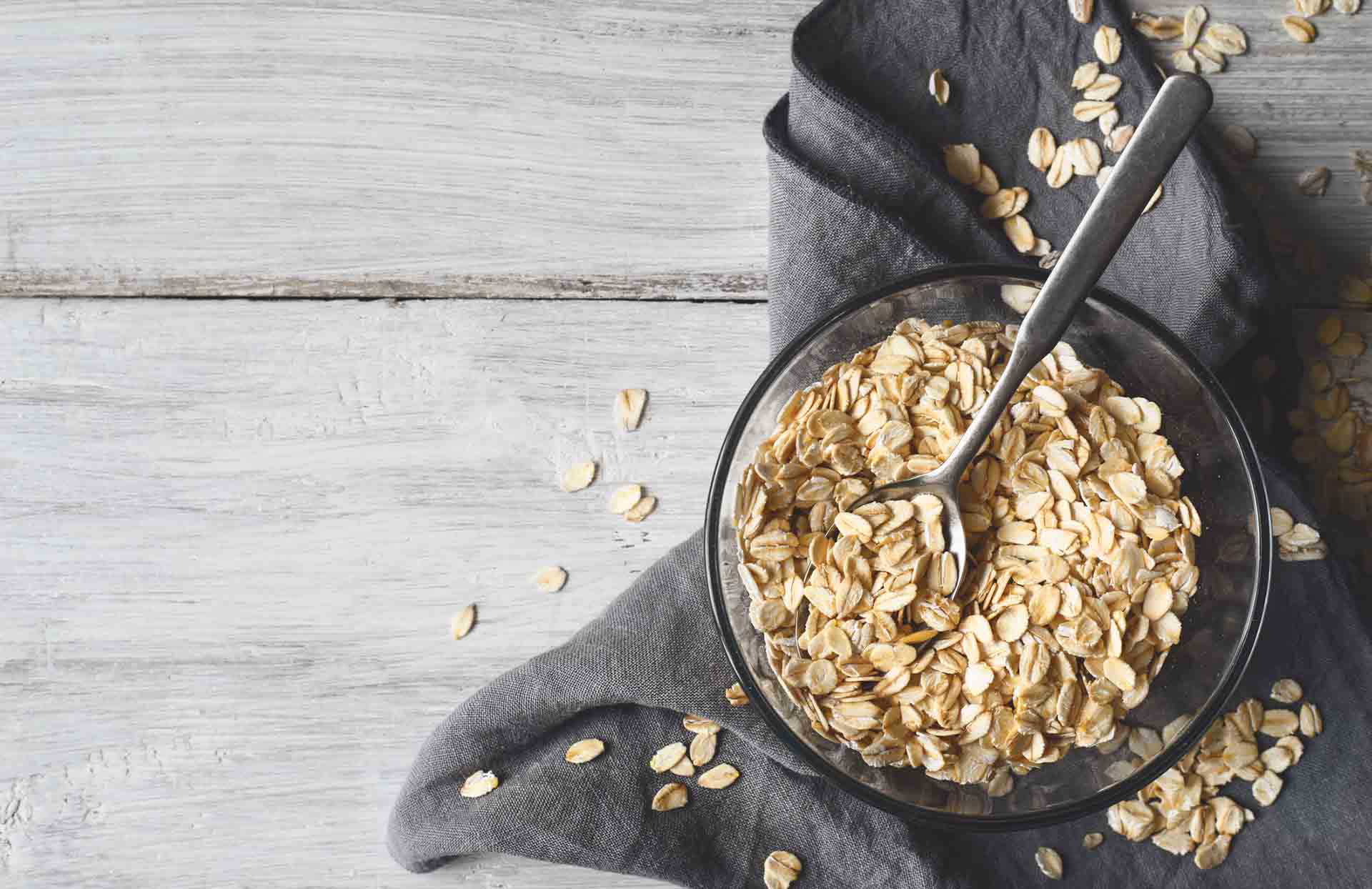 Oat flakes in a glass bowl on a white wooden table