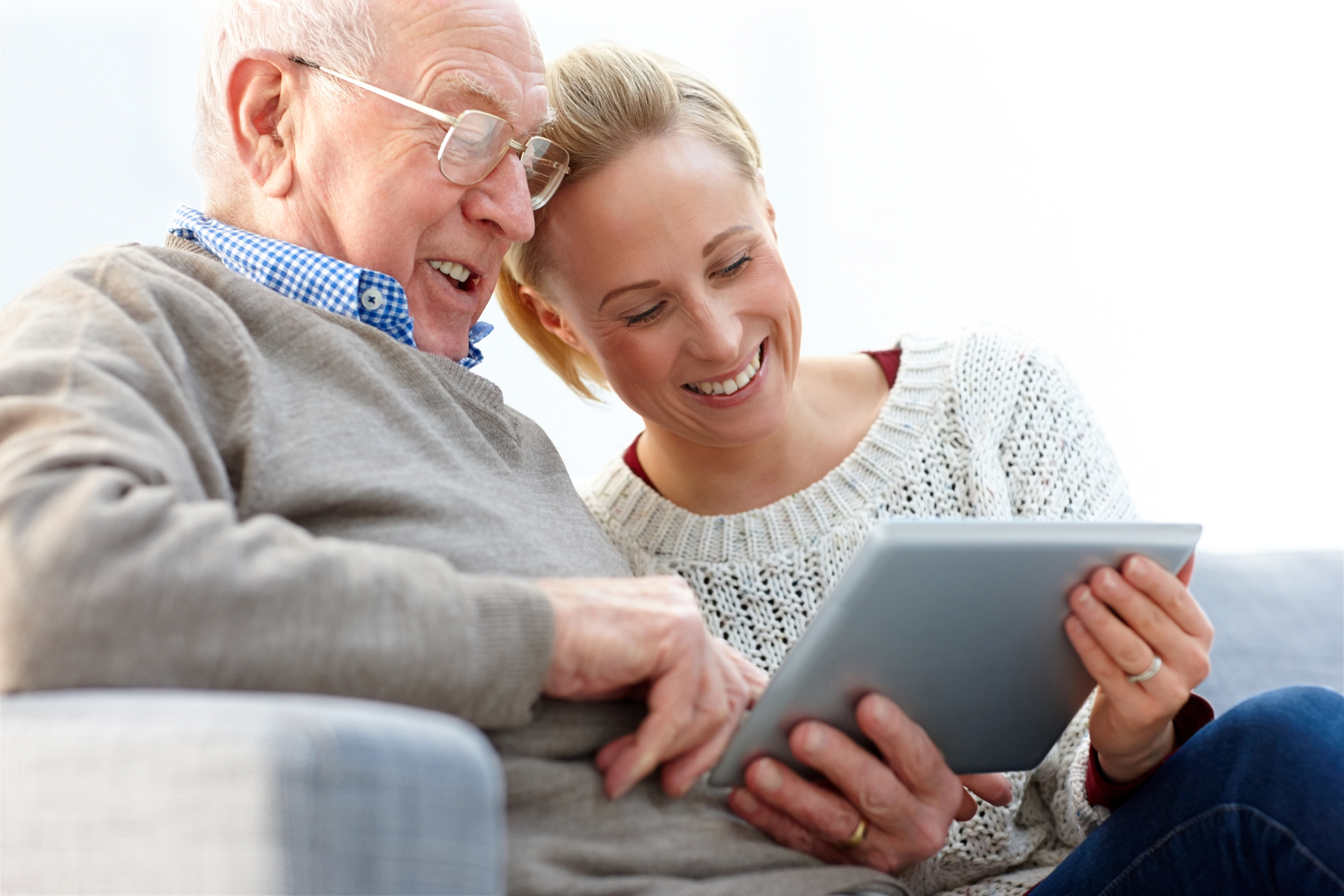 Happy father and daughter sitting on sofa using digital tablet - Indoors