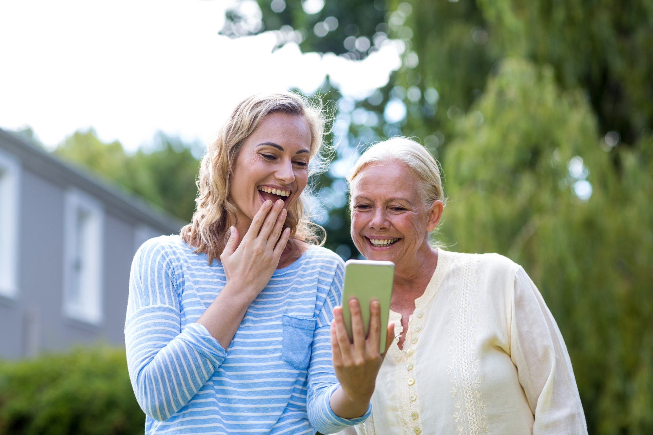 Surprise granddaughter showing phone to grandmother