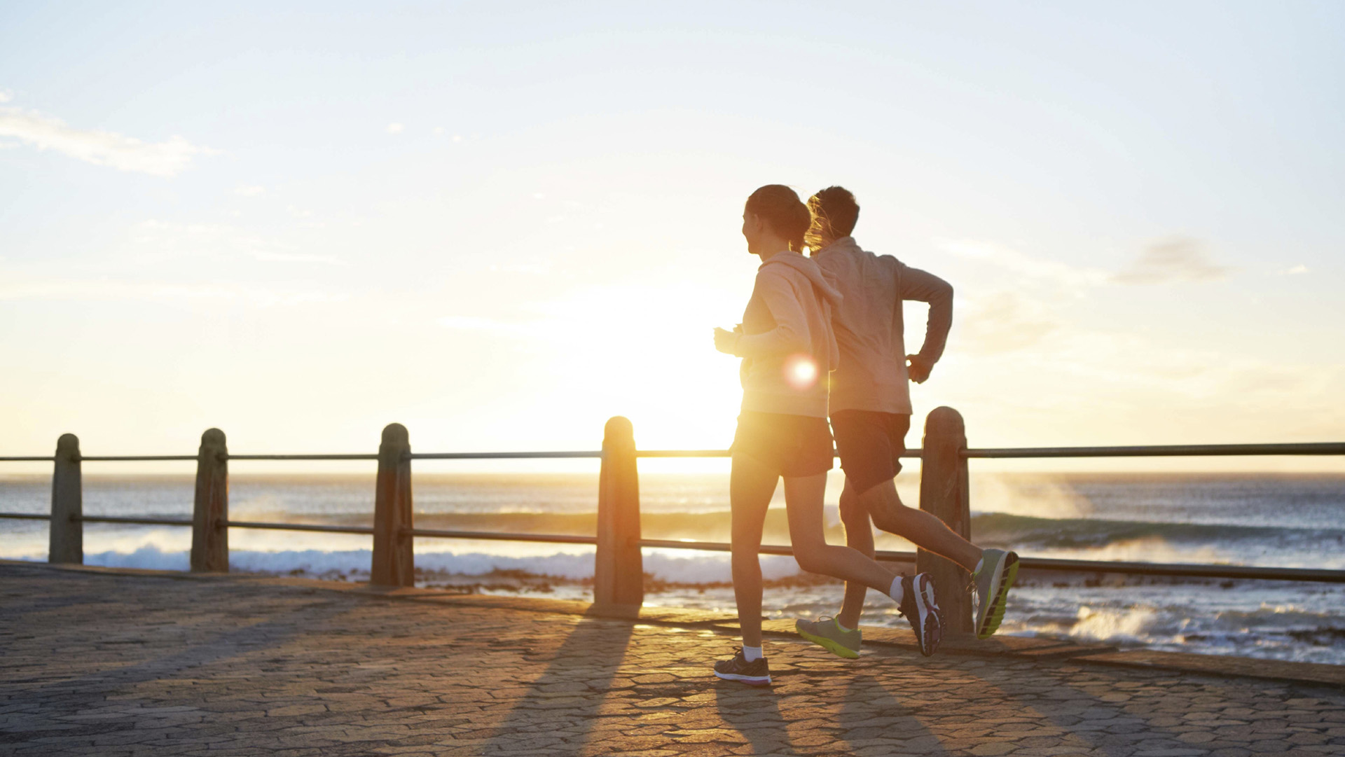 A young couple jogging on the promenade at sunset