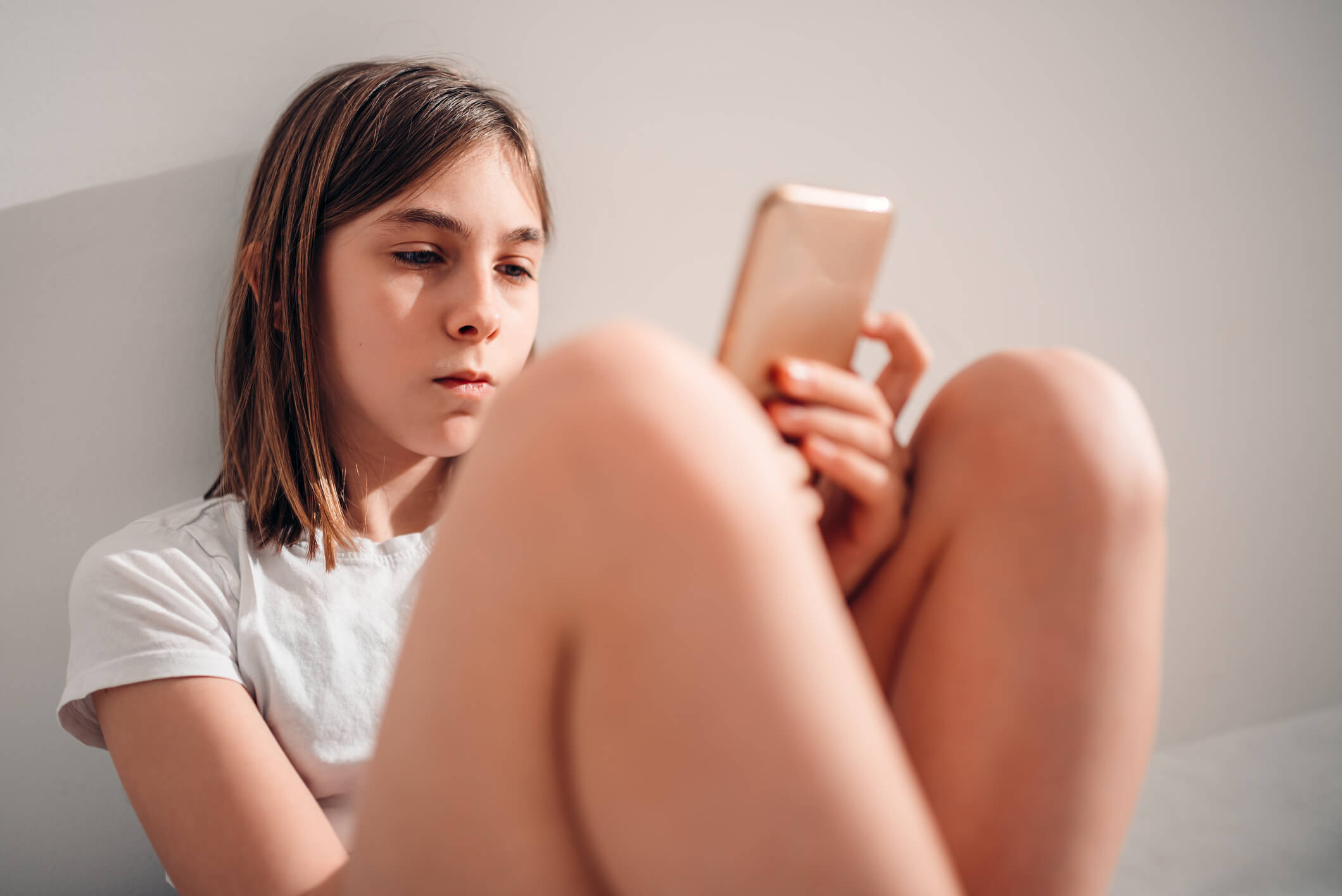 A young girl looks at her smartphone.