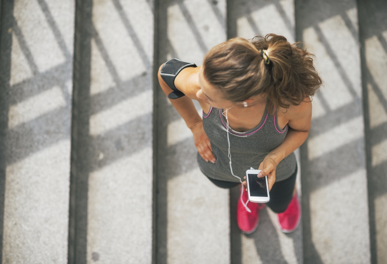 Portrait of fitness young woman with cell phone outdoors in the city