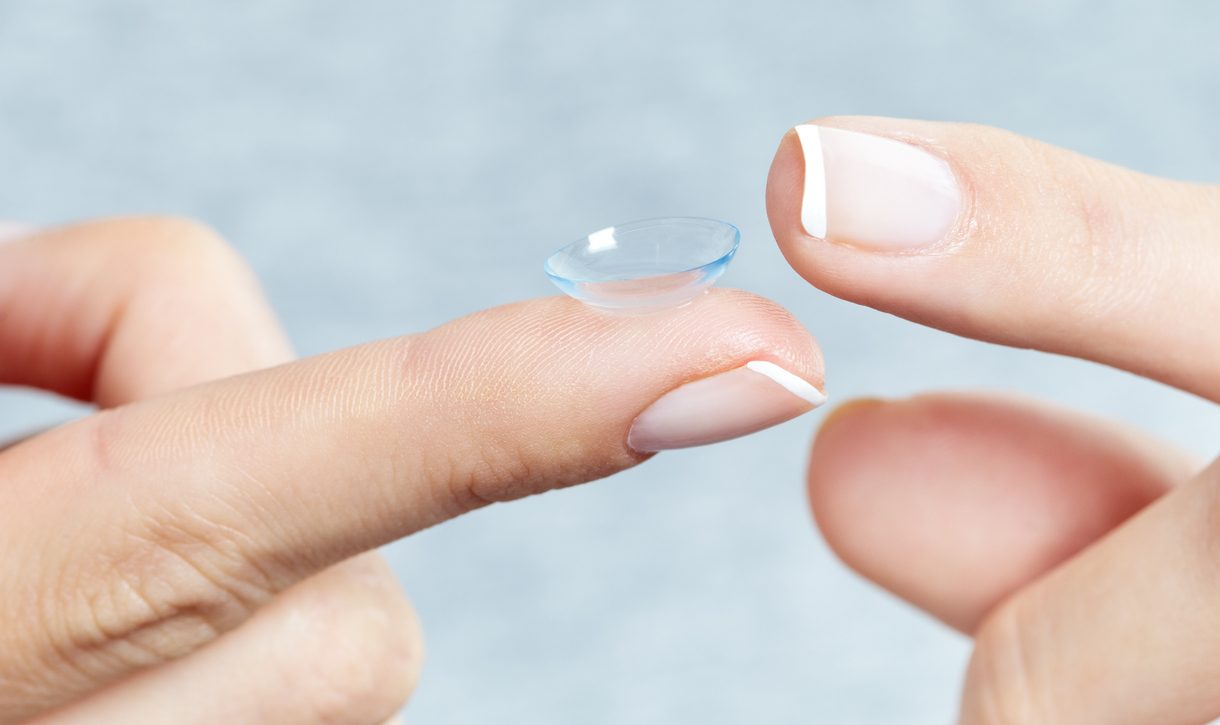 Woman holding a contact lens. Macro studio shot.