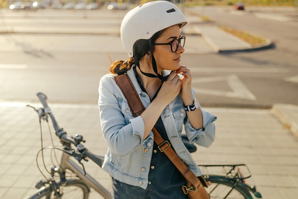 Young woman putting her helmet, preparing for the bike ride