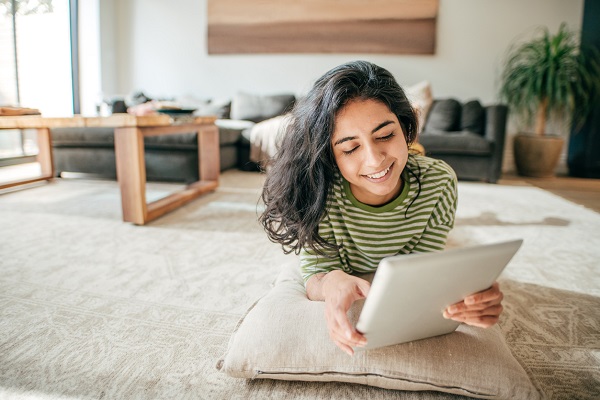 Smiling female student at home with tablet