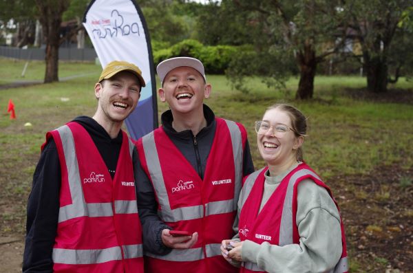 Three happy parkrun volunteers pose for a photo